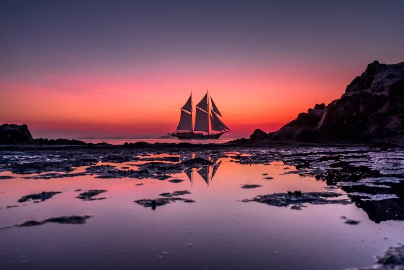 Phinisi yacht under sail at sunset in Komodo National Park