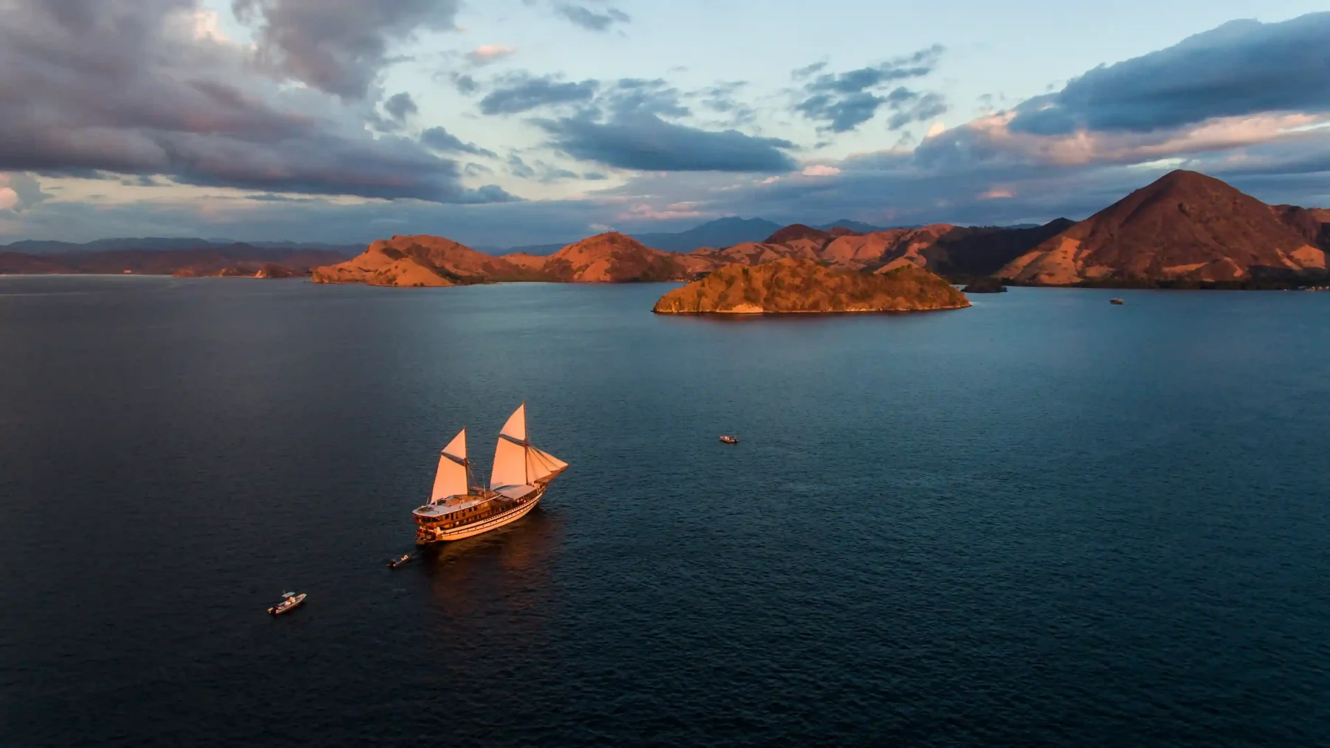 Aerial view of a phinisi sailing among the islands of Komodo at dusk