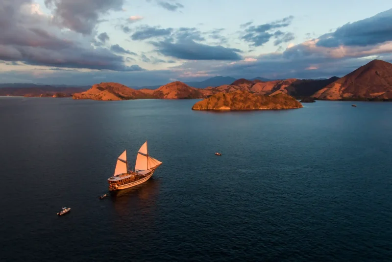 Aerial view of a phinisi sailing among the islands of Komodo at dusk
