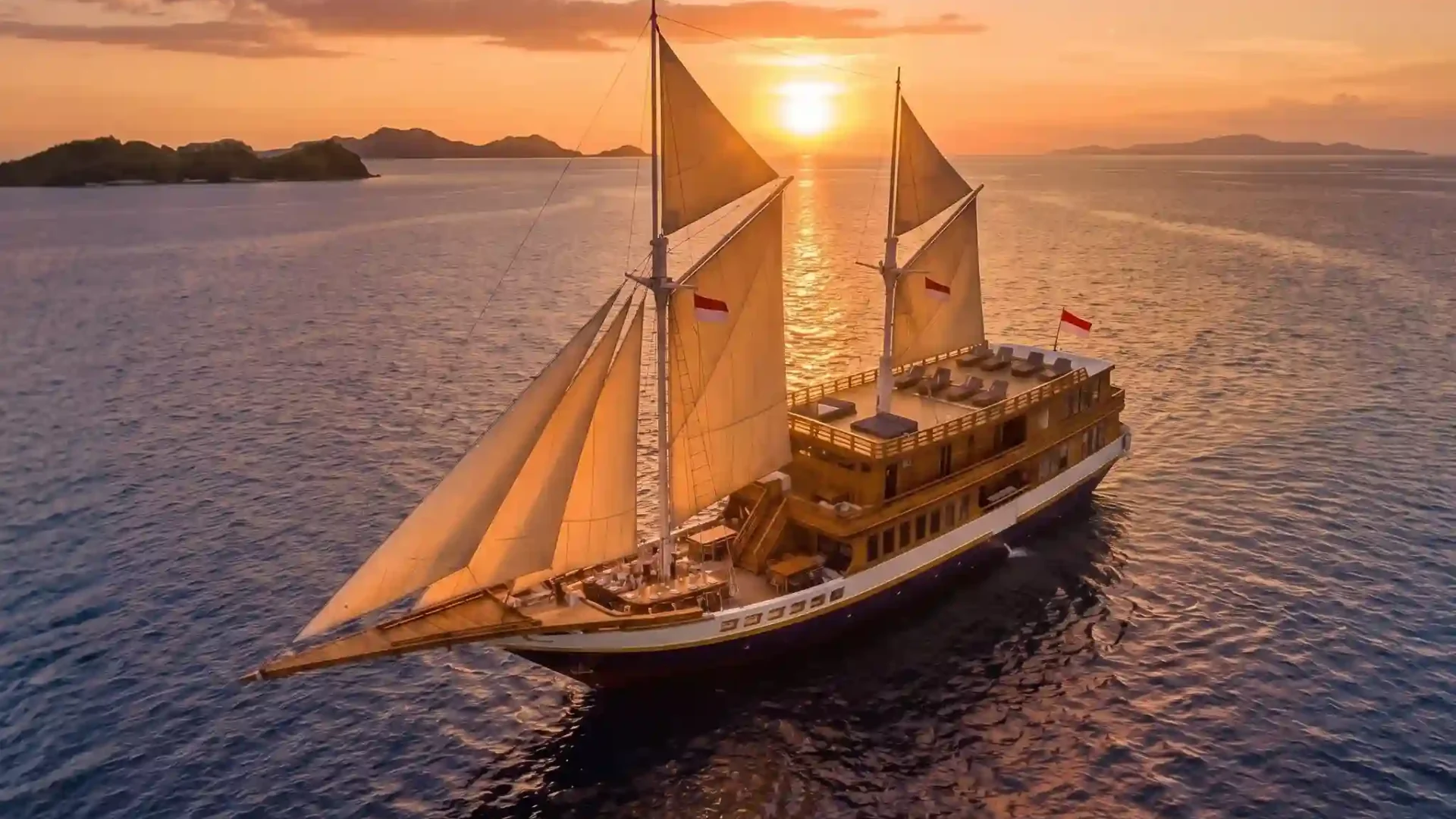 Phinisi yacht under sail at sunset, aerial view