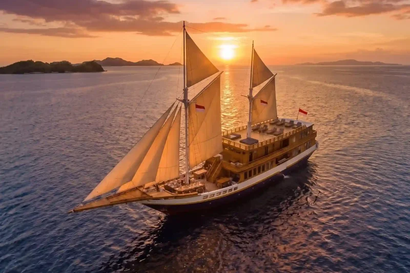 Phinisi yacht under sail at sunset, aerial view