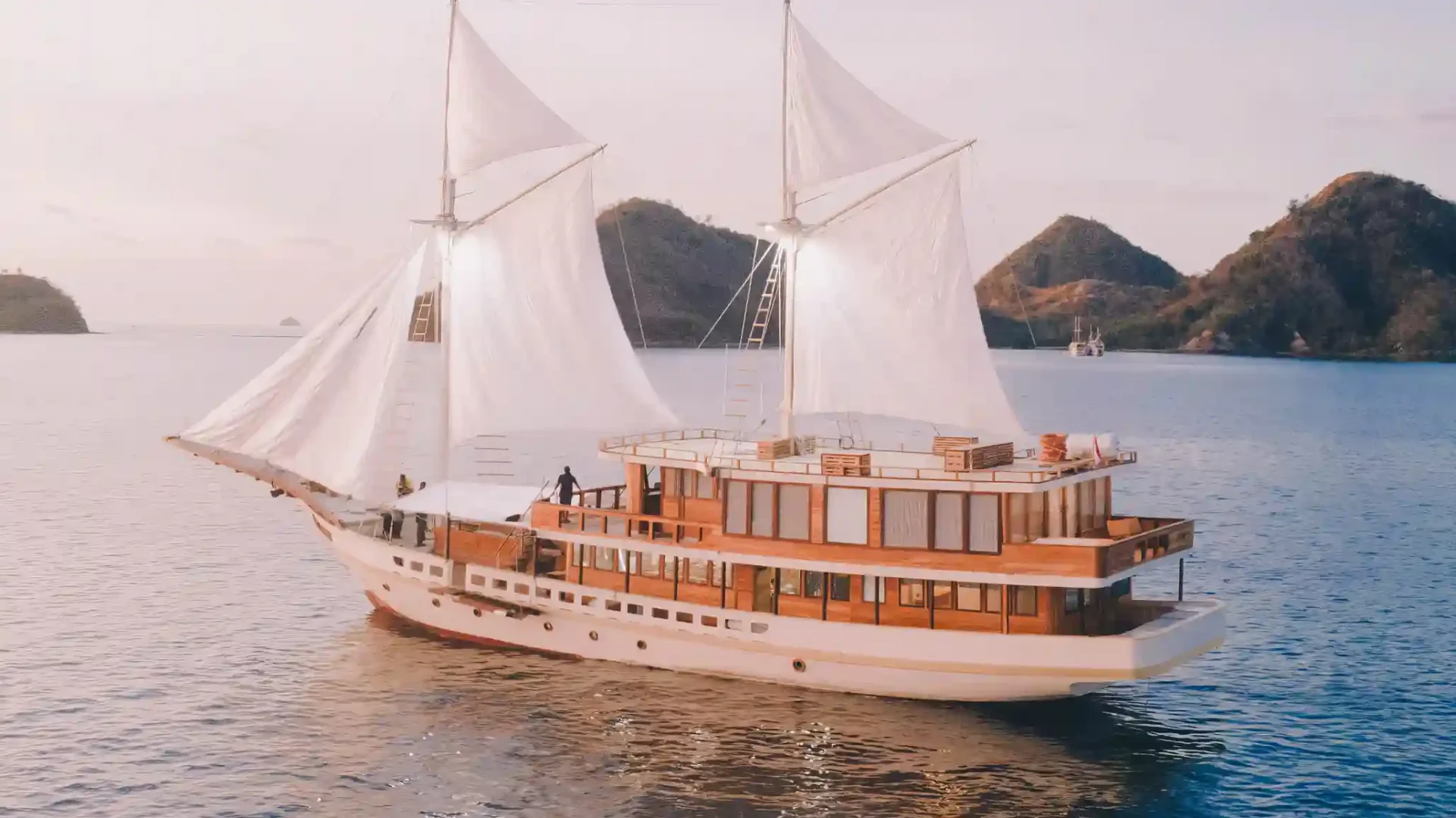 White-sailed phinisi cruising calm waters near Komodo islands