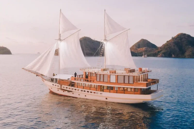 White-sailed phinisi cruising calm waters near Komodo islands