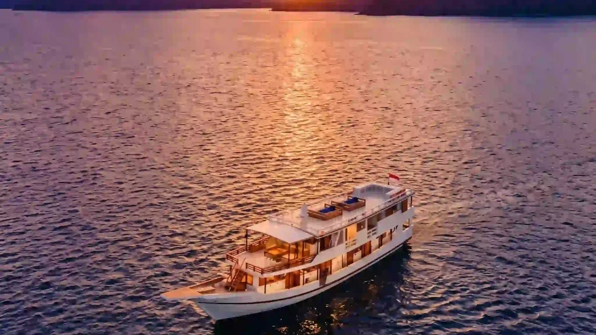 Aerial view of a white yacht at sunset in Komodo