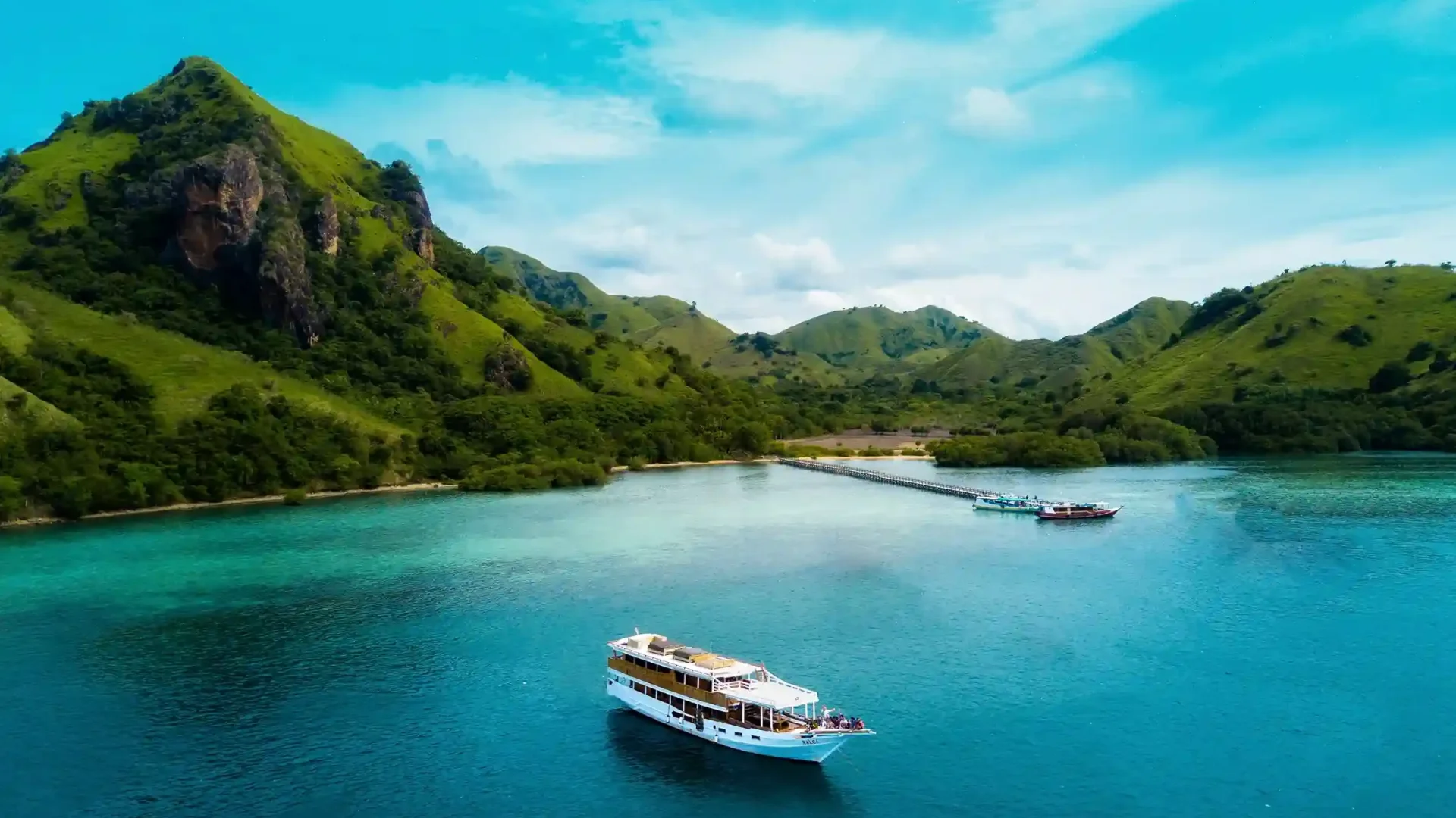 Aerial view of a yacht anchored off a green island in Komodo